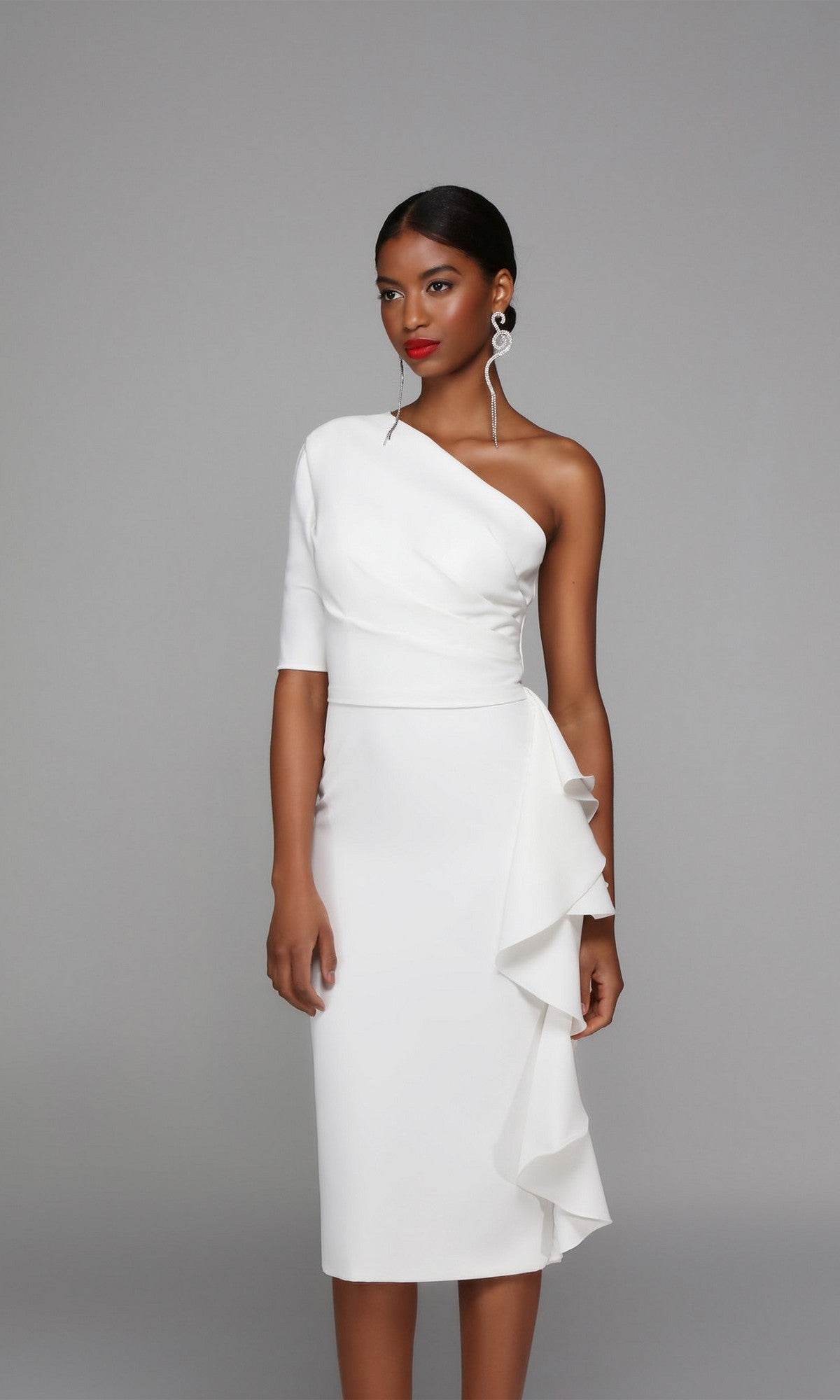 A woman models the Alyce 70006 knee-length semi-formal dress in ivory, featuring a fitted one-shoulder design with a ruffled skirt detail, set against a plain gray background.
